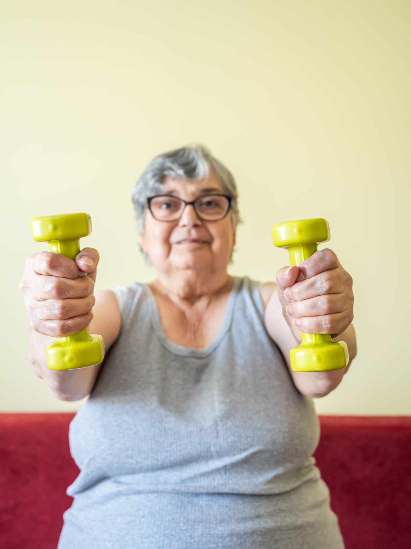 Older woman seated holding two light dumbbells